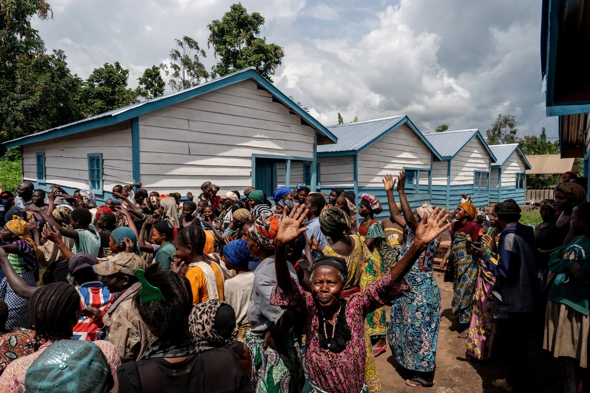 Community members celebrate outside newly built homes in Rutshuru Centre, eastern Democratic Republic of the Congo. After years of displacement, improved housing is helping families return and find stability.