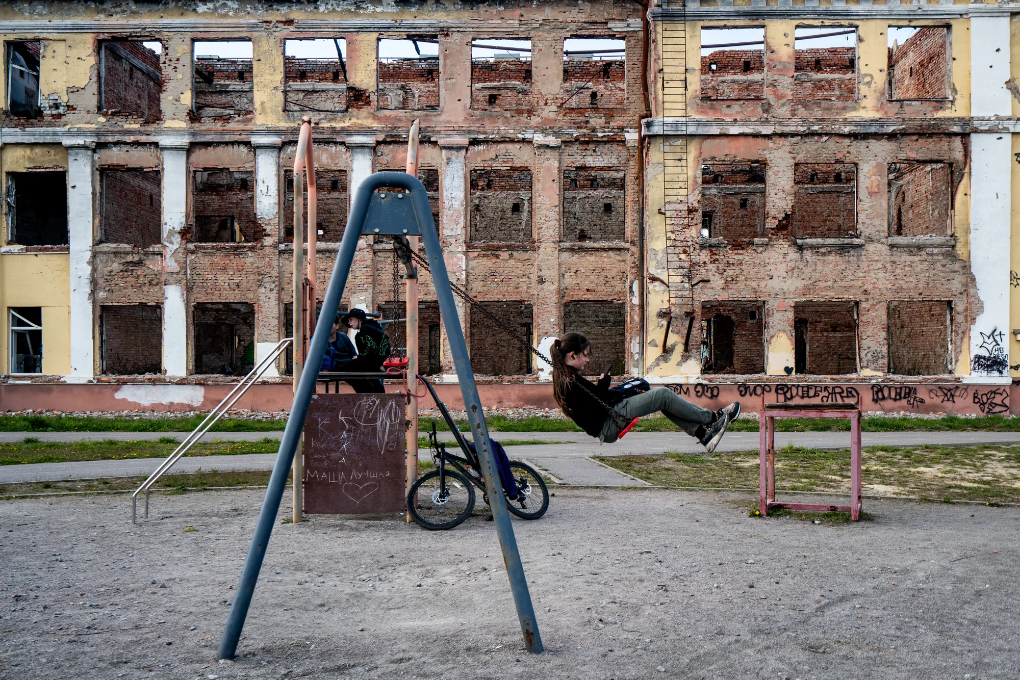A girl plays near the ruins of Kharkiv Specialized School No. 134, destroyed during the early days of the war in Ukraine. Restoring schools and essential infrastructure helps families return and gives children spaces to learn and play.